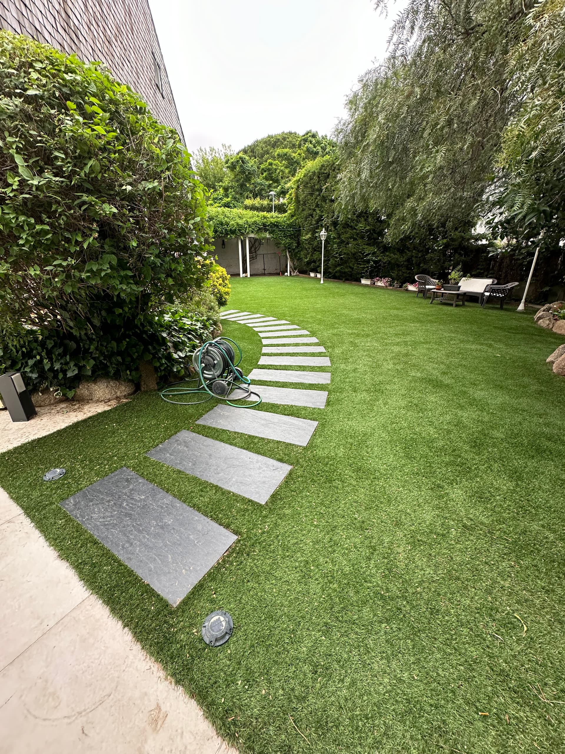 Jardín con césped artificial y camino de losas